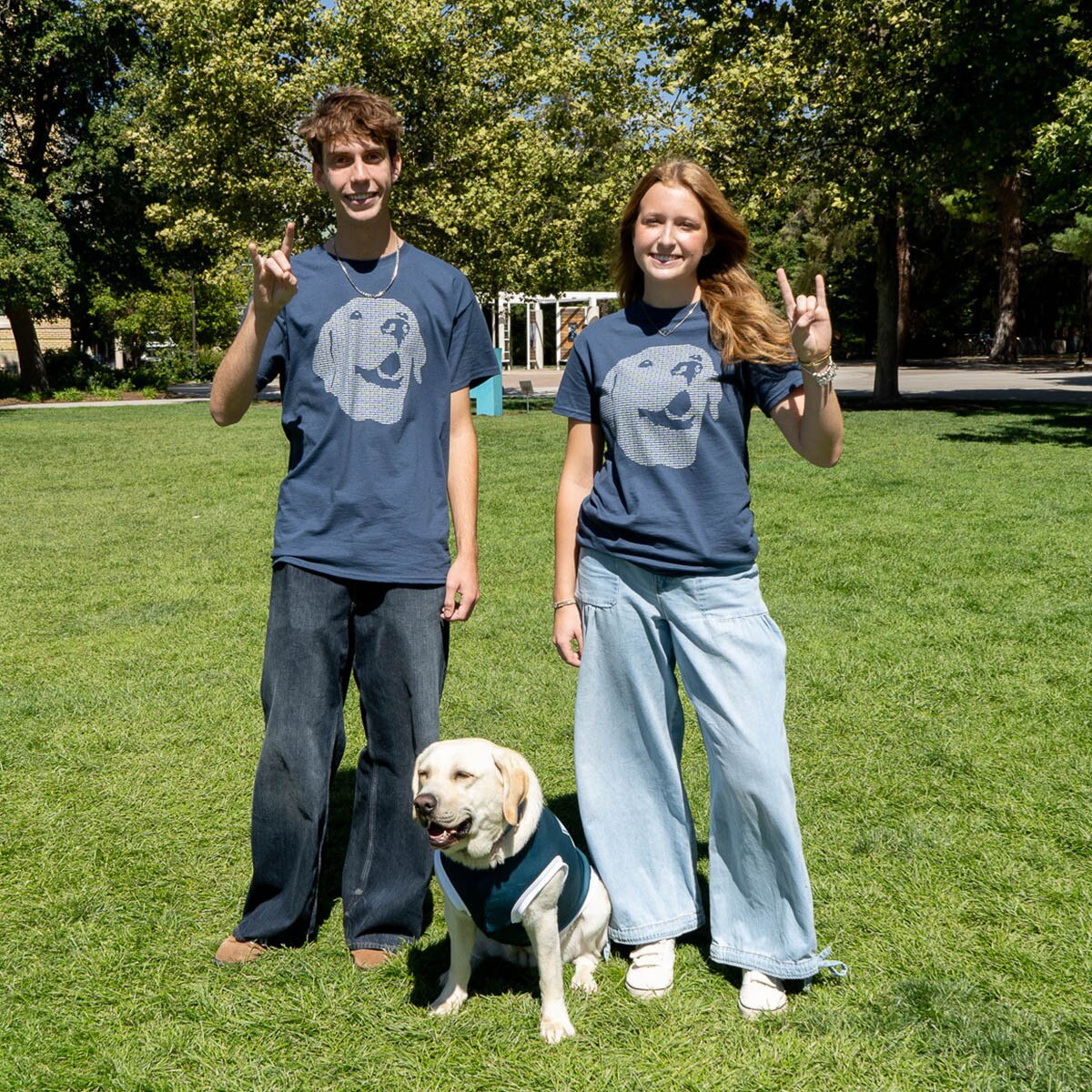 Young man and woman wearing navy sage the dog t-shirts next to Sage